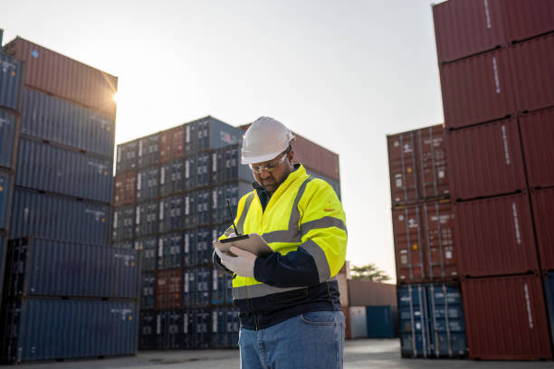 istock Dock worker overseeing operations logistics and shipping yard managing inventory, shipping schedules, or container tracking technology, and safety in the shipping industry, depicting a professional in action at a container yard. 2198707687