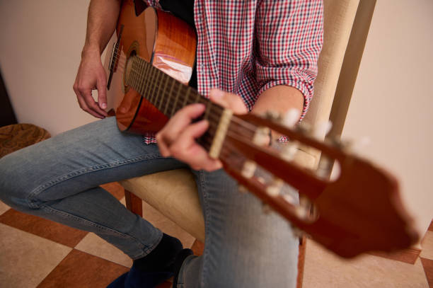 istock Person playing an acoustic guitar while seated indoors 2198707696