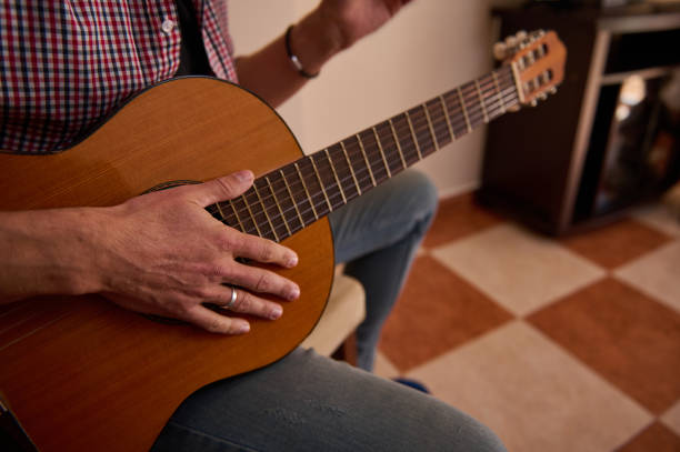 istock Person strumming acoustic guitar indoors with focus on hand and strings 2198707713