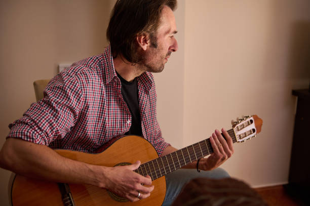 istock Man playing acoustic guitar while seated indoors during daytime 2198707719