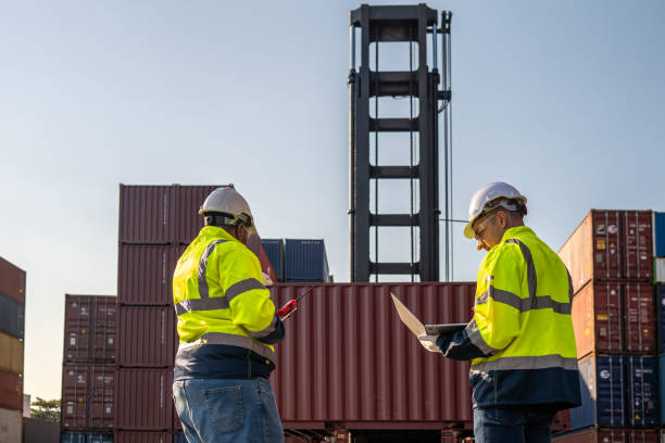 istock Dock worker overseeing operations logistics and shipping yard managing inventory, shipping schedules, or container tracking technology, and safety in the shipping industry, depicting a professional in action at a container yard. 2198707736