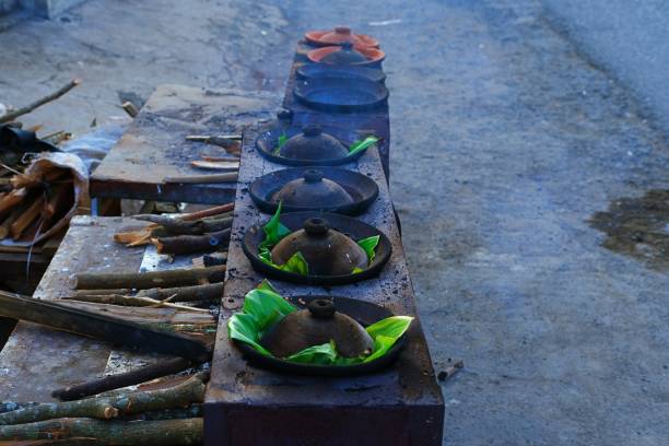 istock Traditional serabi-making process using clay pans lined with banana leaves on a rustic wood-fired stove. 2198708881