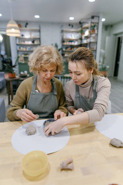 istock Teacher helping retired woman shape ceramic piece at indoor pottery class 2198709399