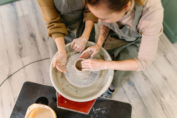istock Mentor guiding elderly student in sculpting pottery on electric spinning wheel 2198710315