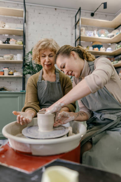 istock Mentor teaches pottery fundamentals, demonstrating sculpting skills on wheel 2198710356