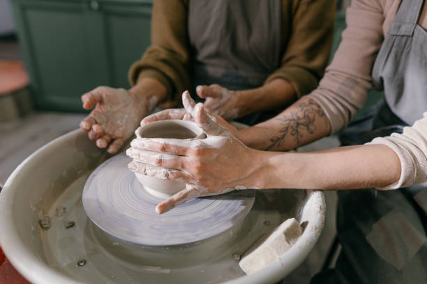 istock Mentor teaches pottery fundamentals, demonstrating sculpting skills on wheel 2198710410