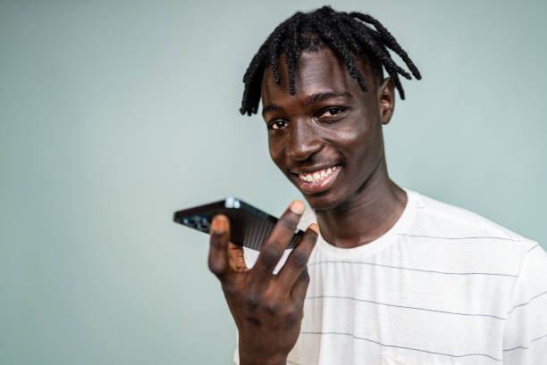 istock Portrait of a young man using mobile phone sending audio message at gray background 2198711839