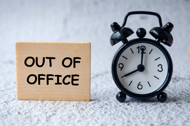 istock Out Of Office text on wooden square with table clock background 2198712222