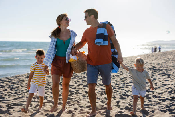 istock Happy family walking on the beach at sunset 2198712626