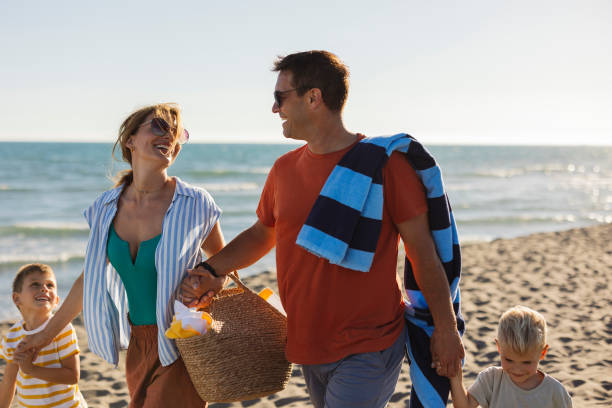 istock Happy family walking on the beach at sunset 2198712663