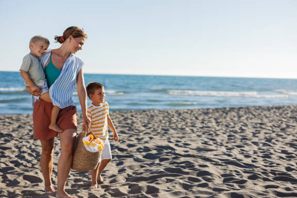 istock Mother and sons walking on the beach carrying a beach bag 2198712674