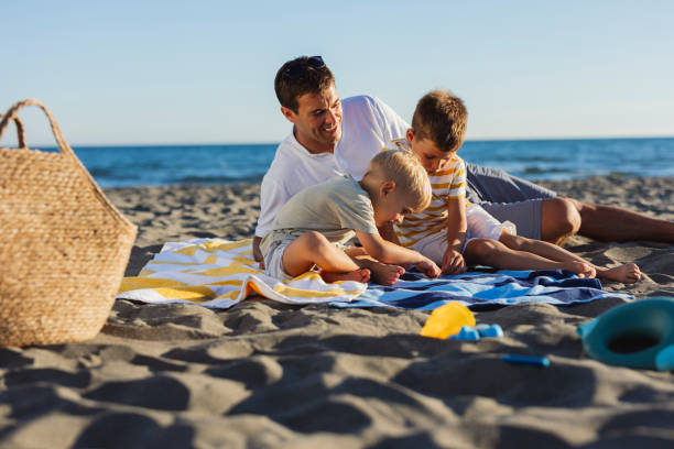 istock Father and sons playing on the beach during summer holidays 2198712872
