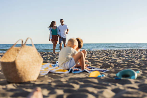 istock Children watching parents walking on the beach during summer vacation 2198712886