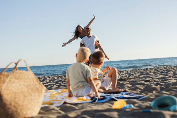 istock Happy family having fun on the beach at sunset 2198713026