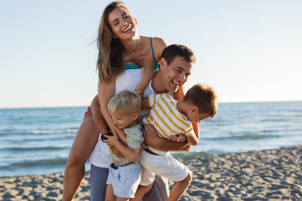 istock Happy family having fun on the beach at sunset 2198713045