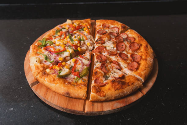 istock Vegetable and sausage pizza cut into pieces on a black table. 2198714334