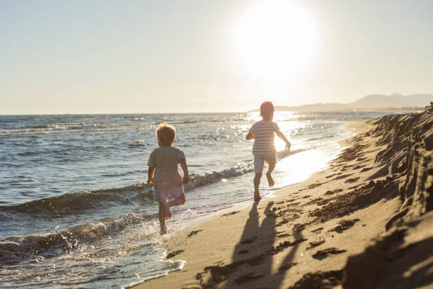 istock Two brothers running on the beach at sunset 2198714457