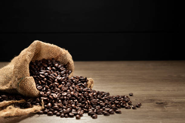istock Roasted coffee beans on a wooden table, dark black background. 2198714673
