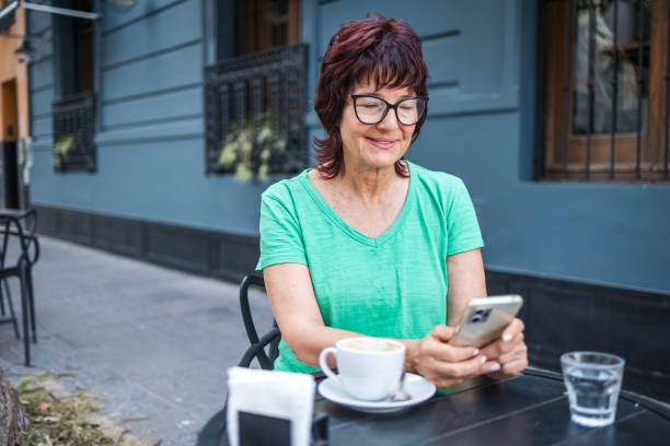 istock Woman enjoying coffee outside while checking her smartphone with a smile 2198717934