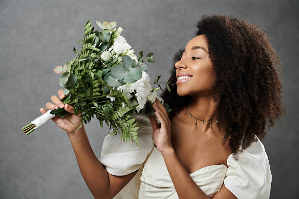 istock Beautiful young woman admires floral bouquet while dressed elegantly in soft light 2198722919