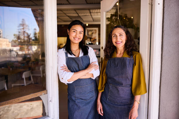 istock Cafe owner and assistant standing in doorway, smiling towards camera 2198723390