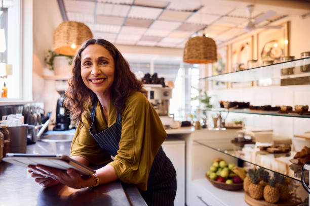 istock Mature female cafe owner using digital tablet and smiling towards camera 2198723449