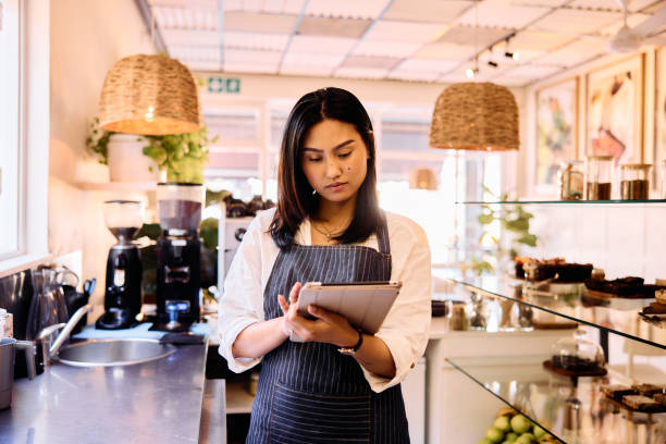 istock Mid adult woman working in cafe using digital tablet, front view 2198723465