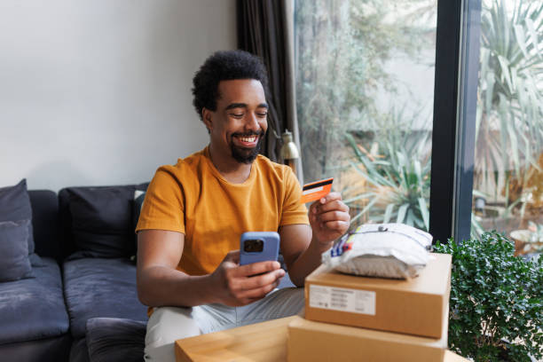 istock Man enjoying online shopping while unpacking delivered packages at home 2198725980