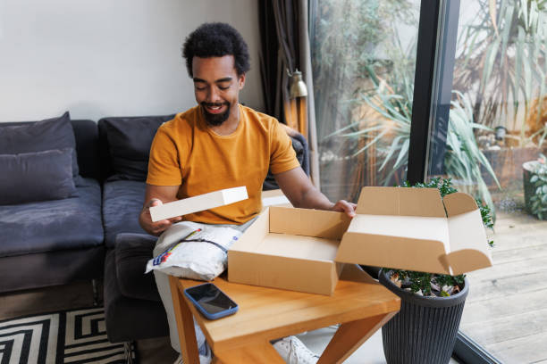 istock Man opening package at home with a smile, enjoying an online purchase 2198725983