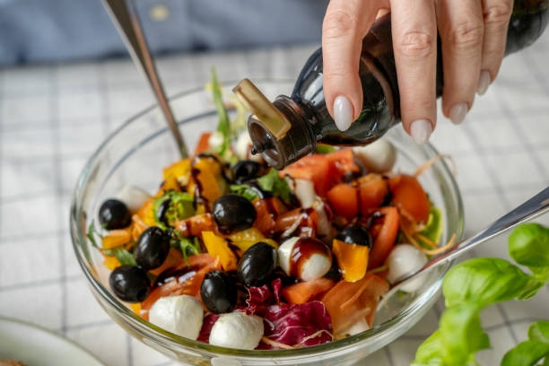 istock Women's hands cooking and mixing salad with tomato  olives mozzarella vegetables arugula dressing with balsamic vinegar and olive oil in a large bowl a healthy balanced meal 2198726123