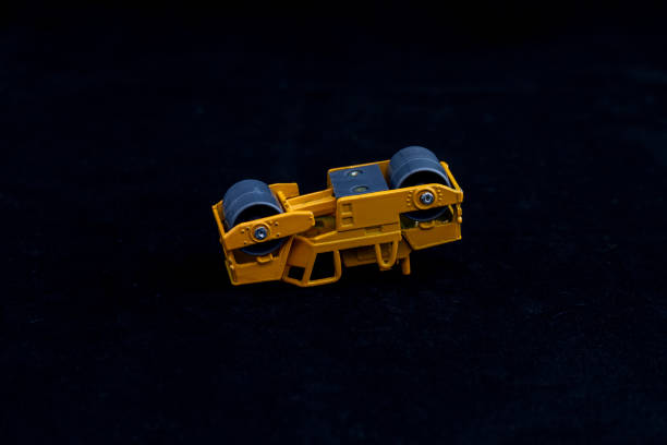 istock Yellow Industrial Roller Miniature with Metal Wheels on Dark Surface 2198726297