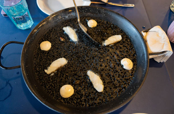 Black rice paella with Cod and allioli. Spanish mediterranean gastronomy.