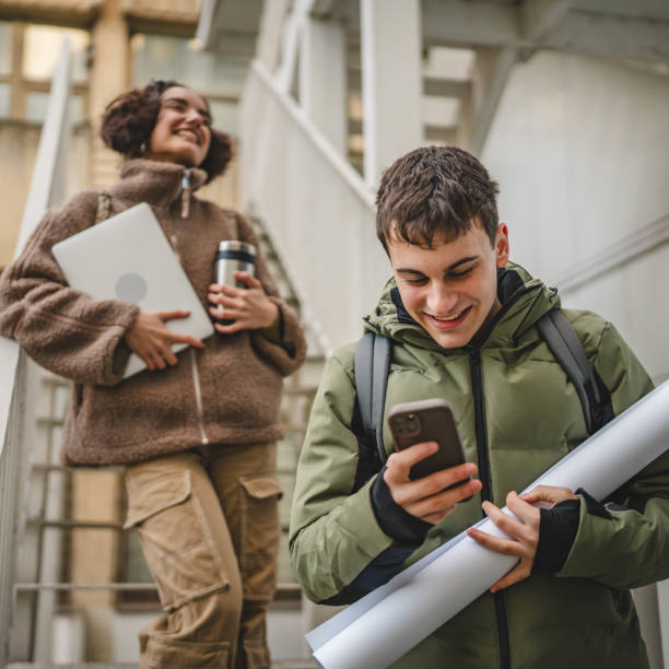 istock young man student stand and use cellphone on stairs on break 2198726588