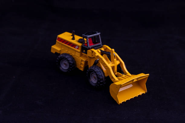 istock Yellow Toy Metal Front Loader Heavy Equipment Machine on Black Background 2198726602