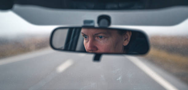 istock Female driver face at car rear view mirror on a rainy day 2198727450