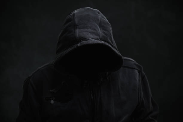 istock Unrecognizable cyber criminal or computer hacker wearing black hooded jacket, low key portrait 2198727500