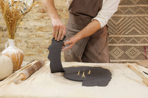 Mature man molding clay on a pottery wheel at ceramics workshop