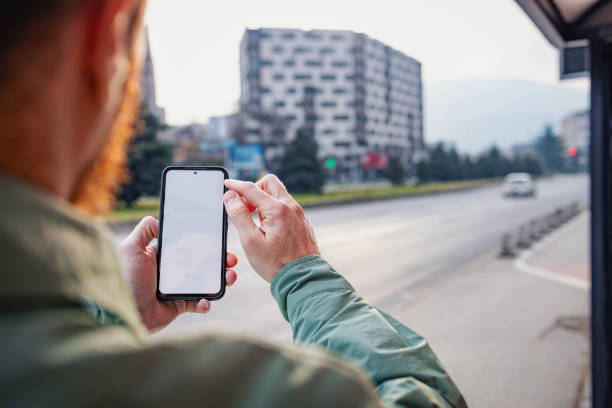 istock Man on a bus station, looking at his phone 2198735423