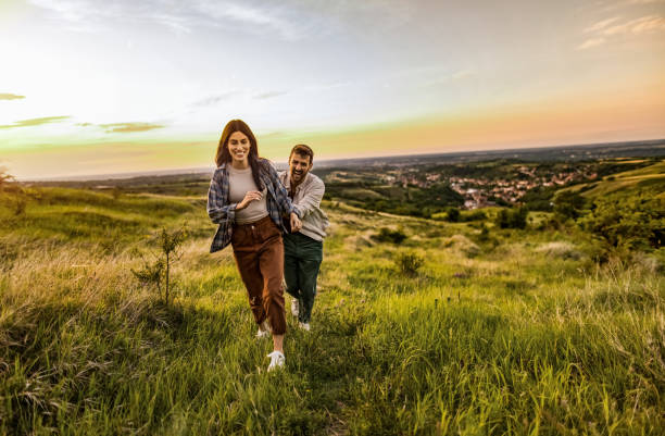 istock Happy young couple having fun running on a grass field in nature 2198735517