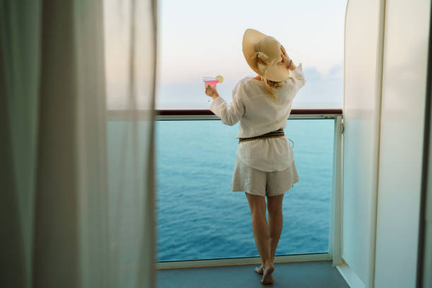 istock A woman with a hat holds a cocktail in her hand while enjoying a cruise 2198736182