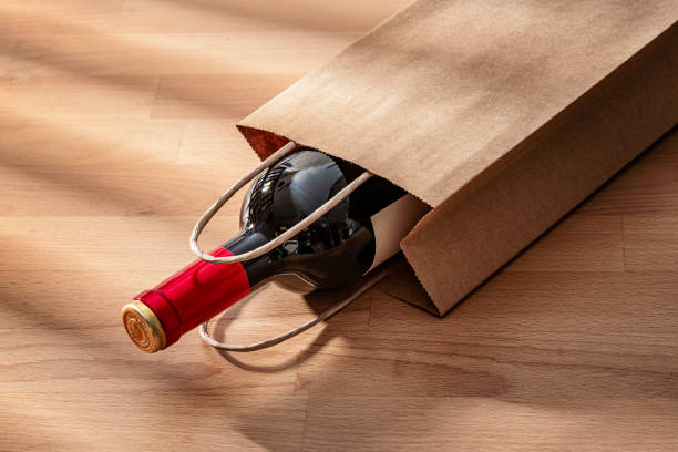 istock Red wine bottle in a paper bag on a wooden background 2198736963