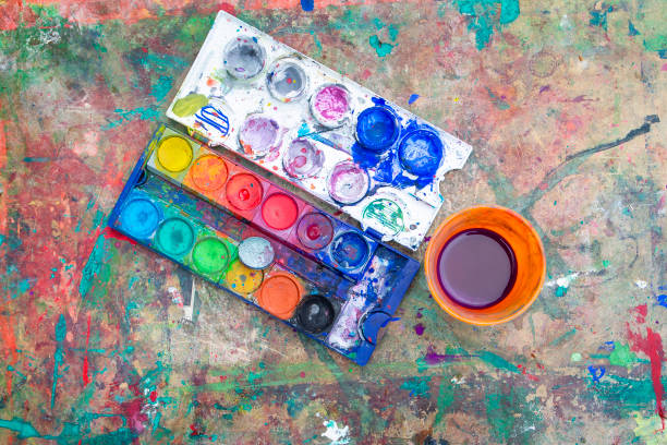 A vibrant watercolor paint box and several paintbrushes