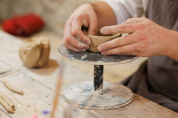 istock Partial shot of potter shaping clay on wheel in blurred workshop 2198737360