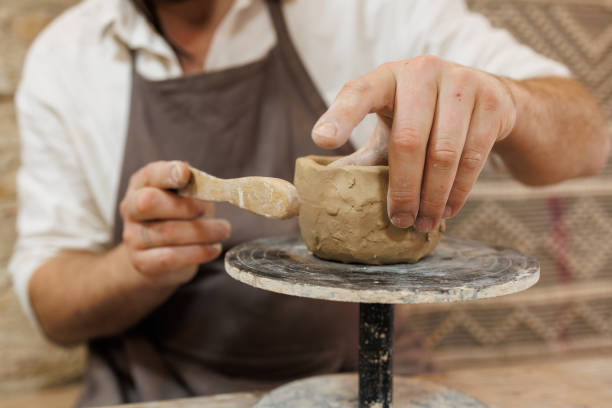 istock Cropped shot of potter modeling clay with wooden tool in studio 2198737508