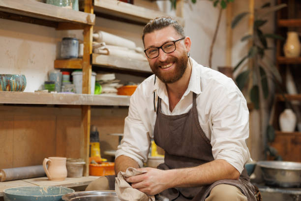 istock Cheerful potter holding towel near pottery wheel in studio 2198738588