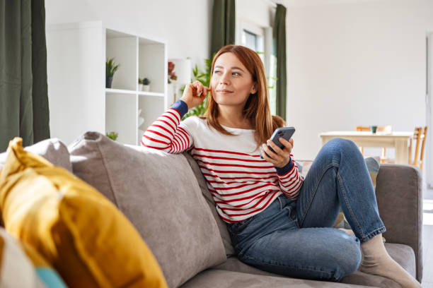 istock Girl Chatting on Mobile While Relaxing on Couch 2198739973