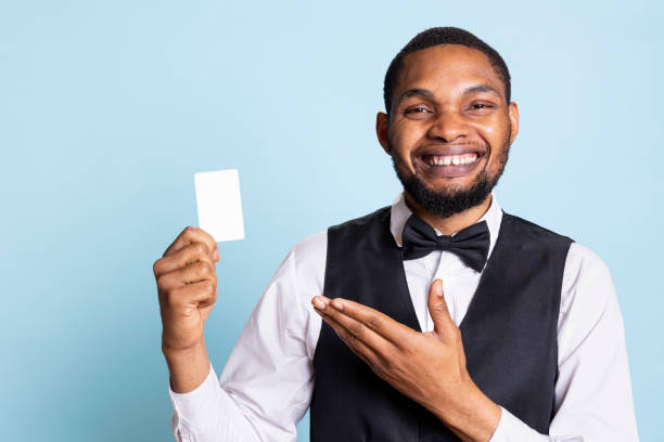 istock Smiling hotel concierge points to the room access card in studio 2198741070