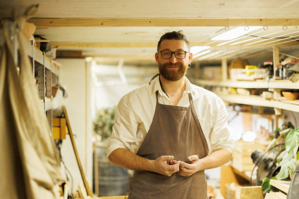 istock Smiling potter looking at camera in blurred storage of studio 2198742384