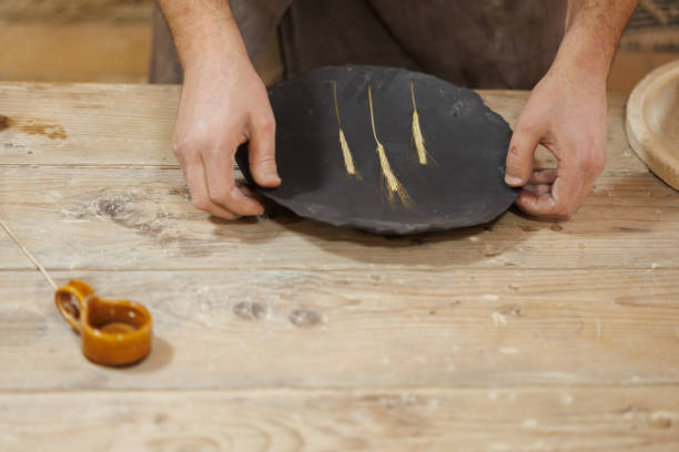 istock Part of artisan holding clay plate with wheat spikelet in workshop 2198742701