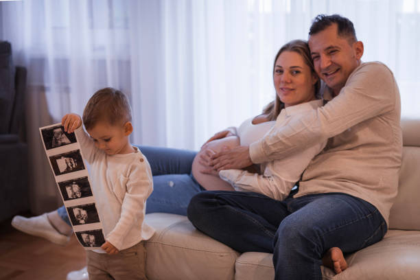 Husband and wife embracing when their son is observing his mother's new baby ultrasound